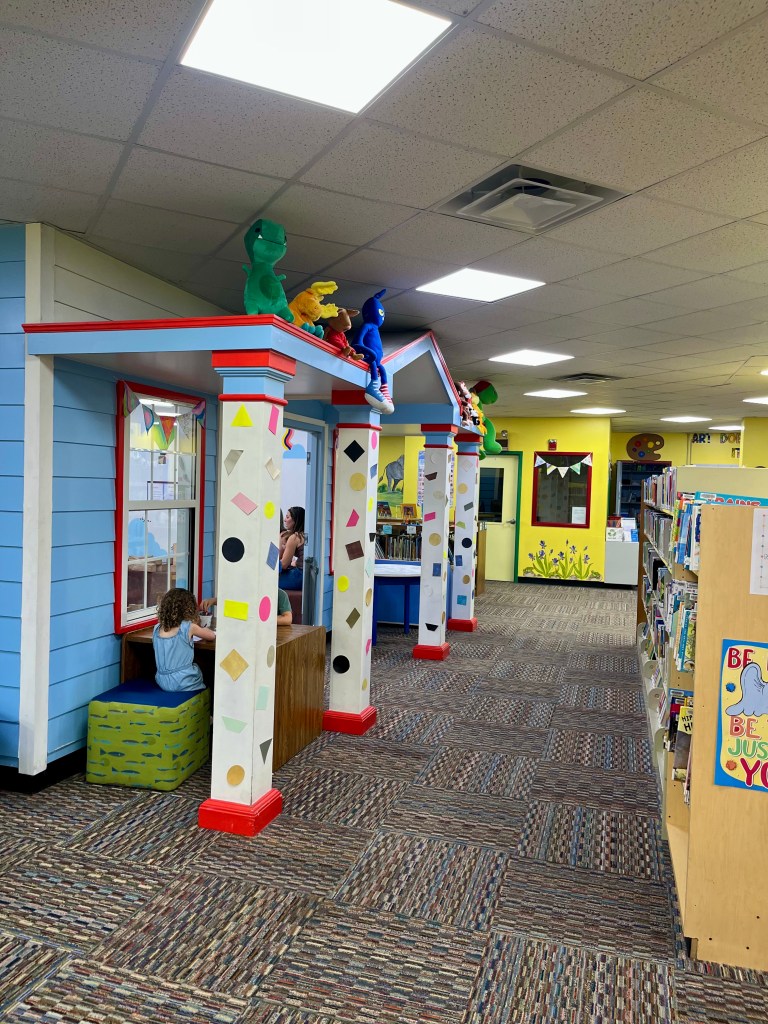 Interior view of the children’s section at Maury County Public Library, showing bookshelves on the right and the play area just outside the frame.