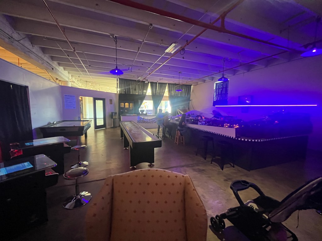 Dimly lit game room at Victory Box with slot car racing on the right and other arcade-style games on the left.