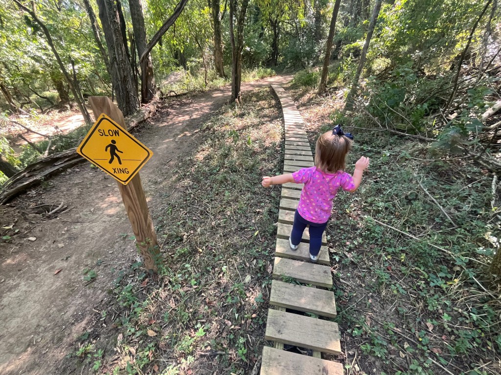 Young girl walking on a wooden trail bridge through Woodland Park in Columbia Tennessee, part of the Columbia TN Kids Guide.